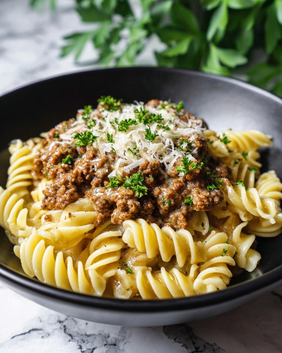 A close-up of a black bowl filled with three main layers: soft yellow pasta with twisted shapes at the bottom, a generous layer of cooked ground meat with a brown color mixed evenly on top, and a light creamy sauce covering the pasta and meat, giving a shiny look. On top, there is a thin layer of grated white cheese and sprinkled small green parsley leaves. The bowl rests on a white marbled surface with a blurred green plant in the background, and the photo is taken with an iphone --ar 4:5 --v 7