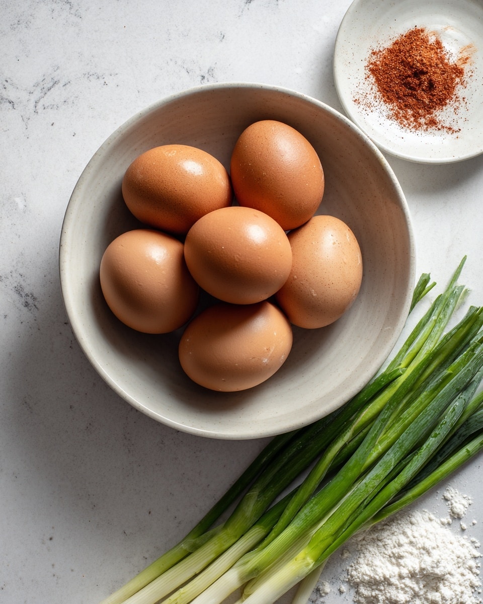 A grey bowl filled with six brown eggs sits on a white marbled surface. To the right of the bowl, there is a bunch of fresh green onions with white roots and long green stalks. Next to the green onions, there is a small white dish with dark blue patterns and a small amount of red spice inside. The whole scene is bright and clean. photo taken with an iphone --ar 4:5 --v 7