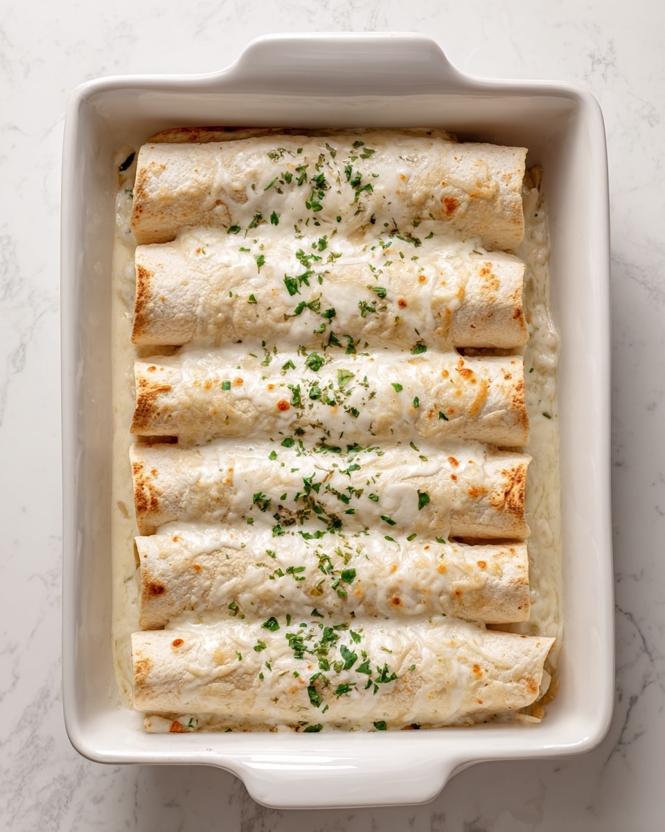 A white rectangular baking dish filled with six rolled tortillas arranged in one row inside. The rolls are covered with a creamy white sauce that spreads evenly over the top, with a few bits of green herbs sprinkled on top. The edges of the tortillas show a light golden color with some spots of sauce. The dish sits on a white marbled surface. photo taken with an iphone --ar 4:5 --v 7