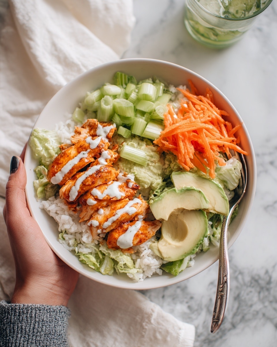 A white bowl holds a colorful dish with four main layers. On the left side, there are four pieces of reddish-orange grilled chicken with light grill marks, drizzled with a thin white sauce in zigzag lines. Next to the chicken, thinly sliced bright orange carrot strips sit in a small pile. To the right of the carrots, there are chopped light green celery pieces. On the far right side of the bowl, a bed of white rice fills the space, with a couple of slices of green avocado placed on top near the celery. A silver spoon rests inside the bowl at the rice side. The bowl is placed on a white marbled surface. Photo taken with an iphone --ar 4:5 --v 7