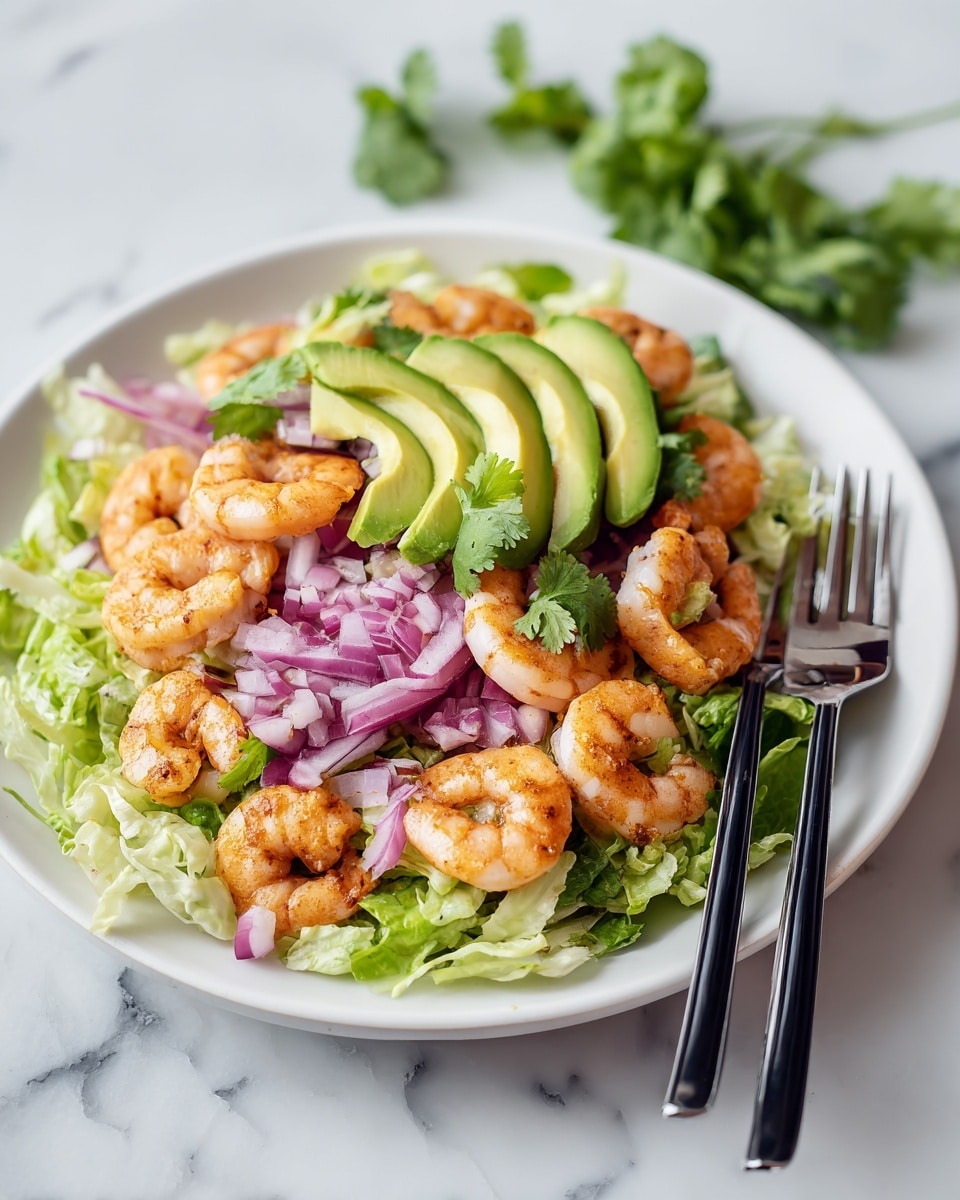 A white deep plate holds a fresh salad with three main layers: at the bottom, shredded green lettuce; in the middle, peeled pink shrimp arranged evenly; and on top, sliced bright green avocado wedges placed around the shrimp. Scattered diced red onions add pops of purple color throughout the salad. Small cilantro leaves are sprinkled on top for garnish. Two black-handled forks rest inside the plate along the right edge. The plate is on a white marbled surface with a few cilantro sprigs in the background. photo taken with an iphone --ar 4:5 --v 7
