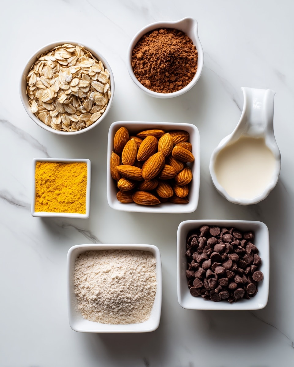 The image shows a top view of several white dishes and containers arranged on a white marbled surface. There is a white bowl filled with light brown rolled oats, a white dish holding whole almonds, and a white measuring cup with a light yellow powder. Another white container holds cocoa powder, and a small white bowl has a bright yellow powder. A white square box of organic coconut milk is also visible, and there is a white bowl filled with dark brown chocolate chips. Each ingredient’s texture and color contrast nicely against the smooth white marbled background, creating a clean and organized look. Photo taken with an iphone --ar 4:5 --v 7