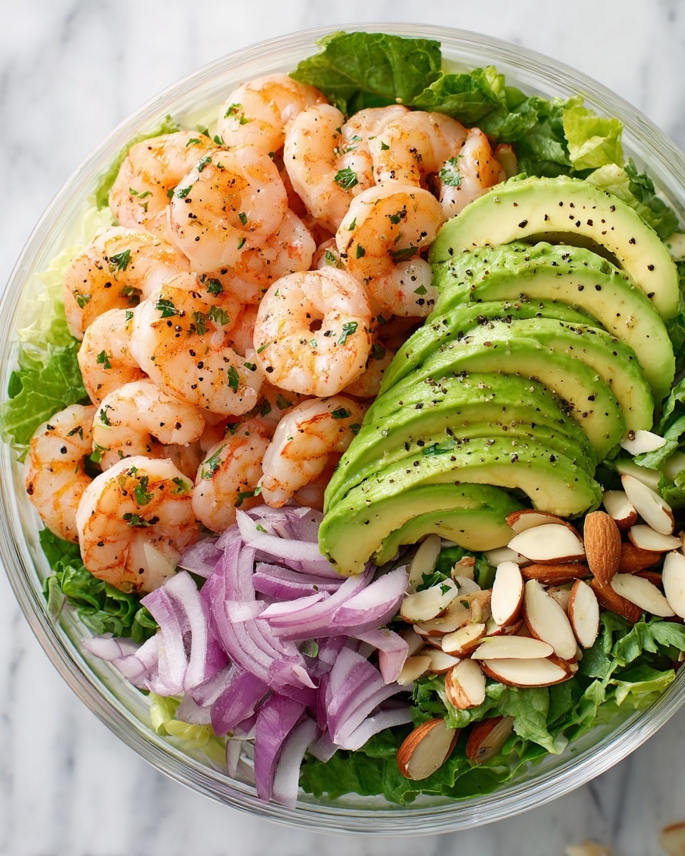 A white bowl contains a fresh salad with three main layers: the bottom layer is green leafy arugula spinach, giving a crisp, textured green base; the second layer is soft, curved slices of pale green avocado placed evenly around the bowl; the top layer is orange-pink cooked shrimp scattered generously across the salad, speckled with small bits of chopped red onion and herbs, along with thinly sliced almonds adding a light crunch. The ingredients have a light dressing with visible black pepper and herbs sprinkled all over. The bowl sits on a white marbled surface photo taken with an iphone --ar 4:5 --v 7