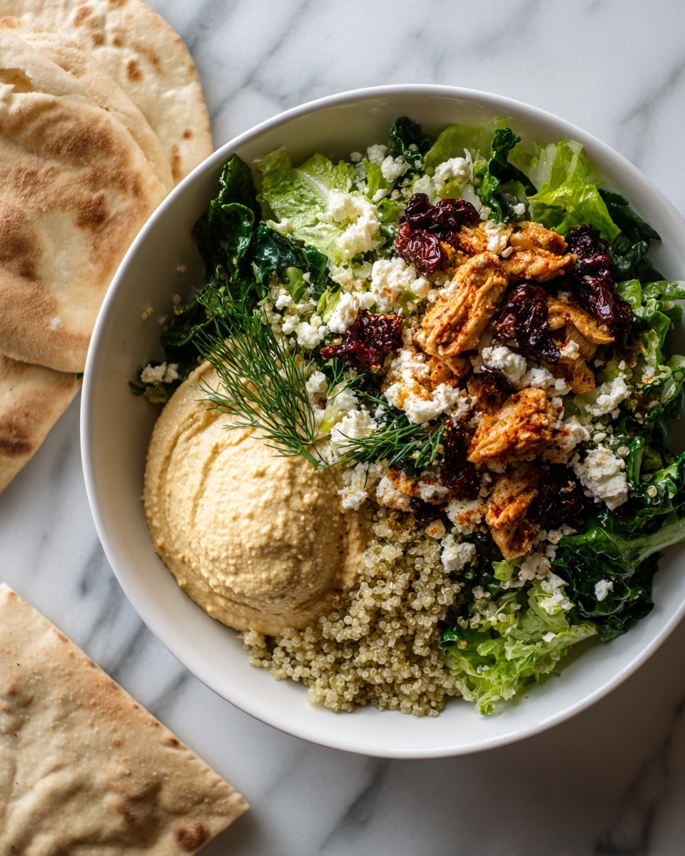 A white bowl sits on a white marbled surface, filled with layers starting from a smooth pale beige hummus spread thickly along one side. On top of this is a layer of finely chopped dark green lettuce that covers most of the bowl's base except the hummus edge. Scattered over the lettuce are small golden-brown roasted chicken pieces with a slightly charred texture, bright white cubes of cheese, bits of deep red sun-dried tomatoes, and a heap of cooked dark reddish-brown quinoa placed near the hummus. Fresh green dill sprigs decorate the bowl's edge. To the left of the bowl, part of a white flatbread rests on the surface, and above the bowl, delicate white and pink wildflowers add a soft, natural detail. photo taken with an iphone --ar 4:5 --v 7