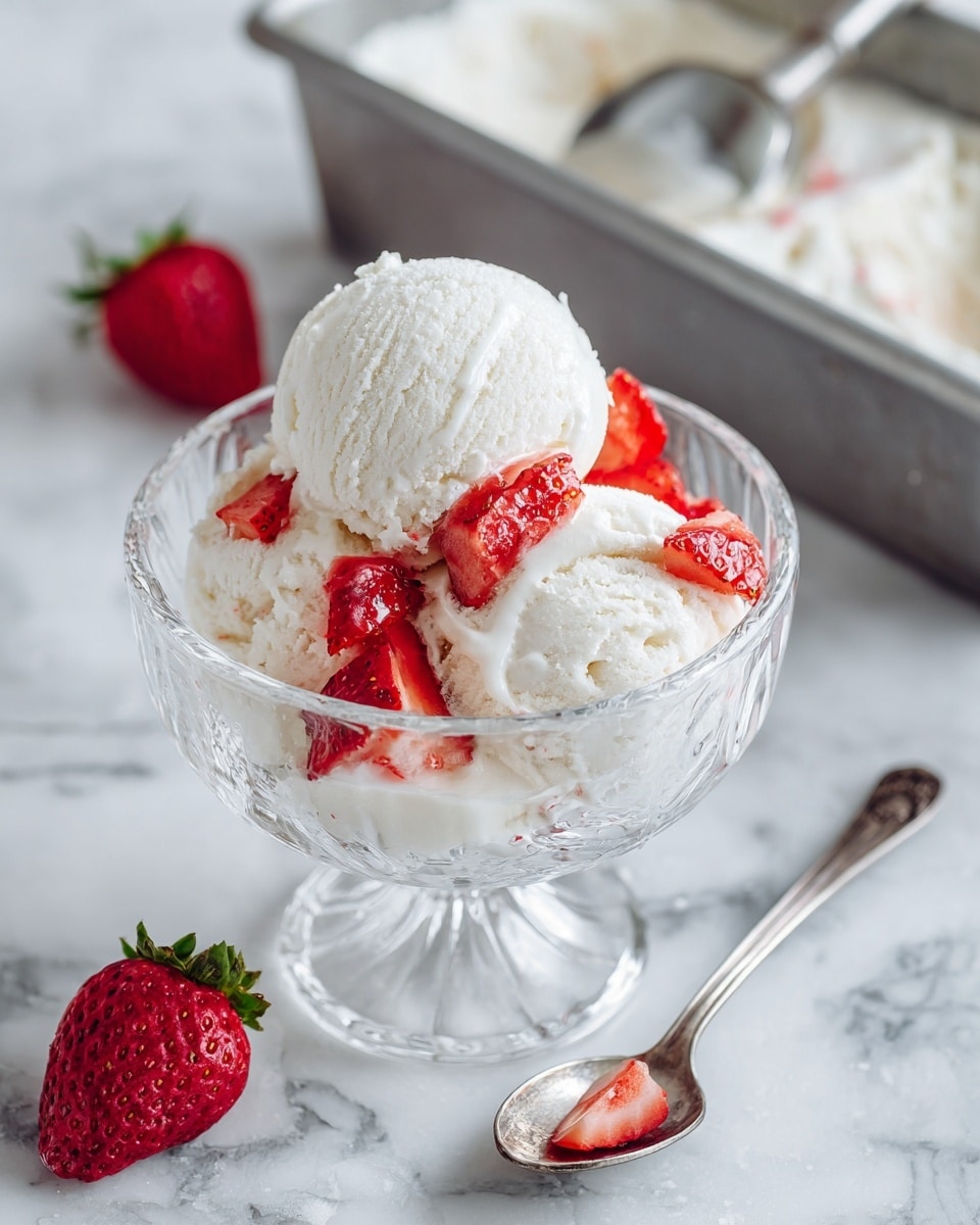 The image shows a white marbled surface with a white bowl filled with two scoops of creamy white ice cream, topped and surrounded by small pieces of bright red strawberries. A silver spoon lies in front of the bowl, and in the background, there is a metal container with more ice cream and a scooping tool. The colors focus on the contrast between the white ice cream and red strawberries, with the blue-tinted bowl adding subtle color to the scene, photo taken with an iphone --ar 4:5 --v 7