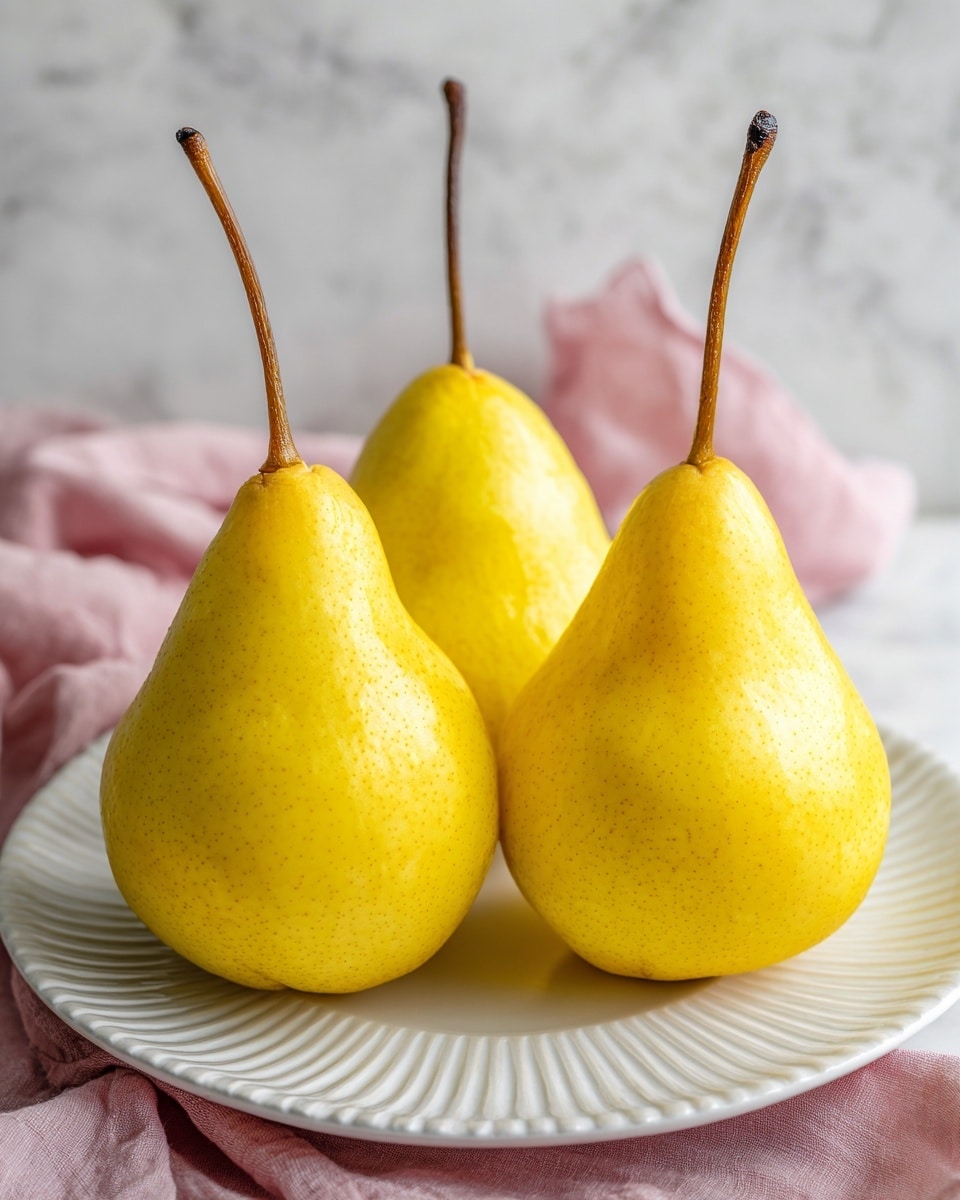 The image shows three yellow poached pears standing upright on a white round plate with ridged edges. The pears have smooth, shiny skin and long, thin brown stems. They are arranged closely together near the center of the plate. The plate sits on a white marbled surface with a glimpse of a soft pink fabric beneath the plate on the bottom right side. The lighting highlights the bright yellow color and smooth texture of the pears, creating a fresh and simple presentation. photo taken with an iphone --ar 4:5 --v 7