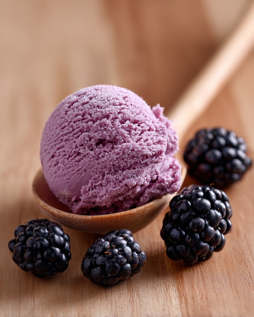 The image shows a single scoop of purple-pink ice cream resting in a wooden spoon, placed on a light wooden surface next to four fresh blackberries scattered around. The ice cream scoop has a smooth, rounded texture with tiny ice crystals visible, while the blackberries are deep black-purple with shiny, bumpy surfaces. The warm tones of the wooden background contrast with the cool colors of the ice cream and berries. photo taken with an iphone --ar 4:5 --v 7