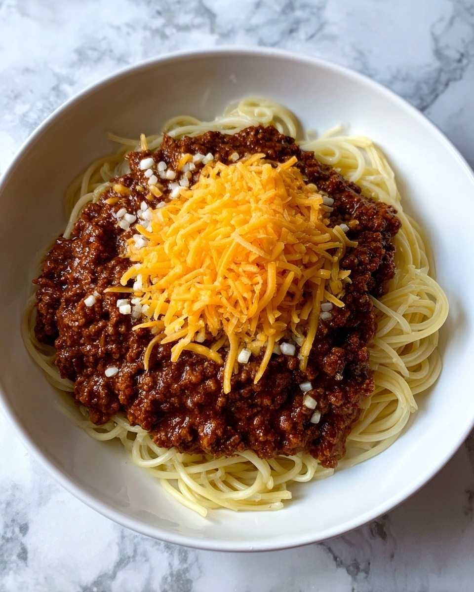 A white bowl filled with a base layer of spaghetti noodles, spread evenly across the bottom. On top of the noodles is a thick layer of dark brown chili with visible kidney beans mixed throughout. Scattered white chopped onions are seen atop the chili, adding a bit of contrast in color. The central part of the bowl is heavily covered with a bright orange shredded cheese mound. Small, round, pale yellow cracker pieces are spread over the cheese and chili layers, some inside the bowl and some outside on a white marbled surface. A fork with a red handle is placed on the right side of the bowl, resting in the noodles and chili. Photo taken with an iphone --ar 4:5 --v 7